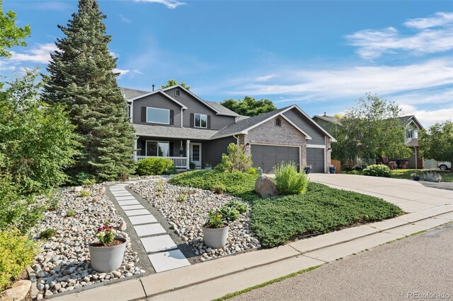 2066 Amber Ct, Erie, CO 80516 - traditional home featuring an attached garage, driveway, covered porch, brick siding, and a shingled roof