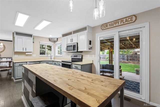 2066 Amber Ct, Erie, CO 80516 - kitchen featuring stainless steel appliances, butcher block countertops, dark wood-type flooring, white cabinets, and decorative light fixtures