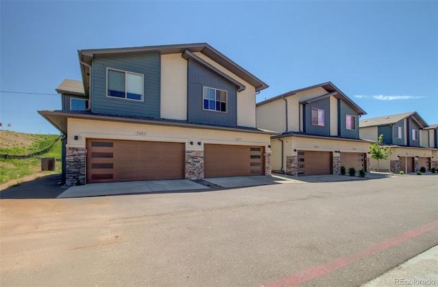 5477 Passport Vw, Colorado Springs, CO 80922 - view of front of property with stone siding, a garage, and central AC