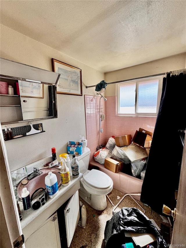 bathroom featuring a textured ceiling, toilet, vanity, and tiled shower