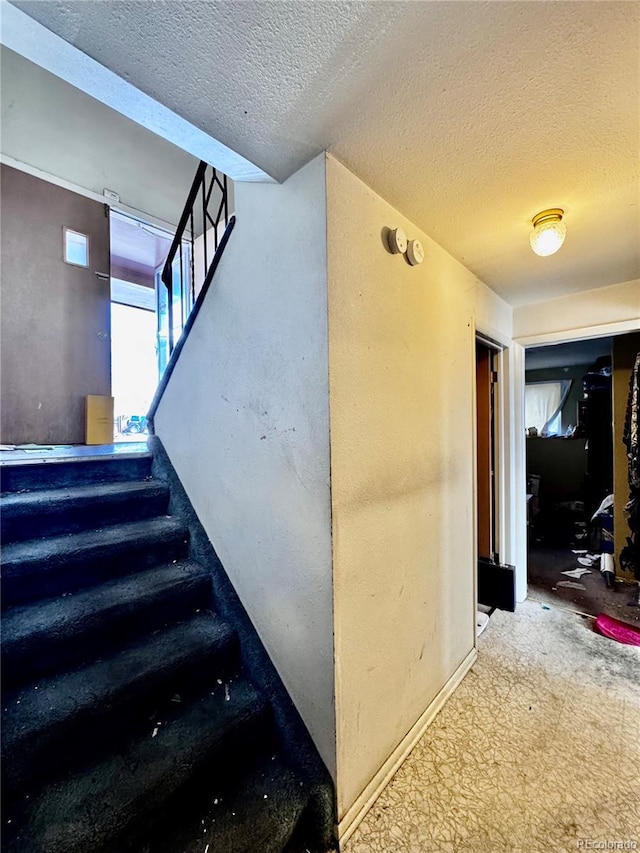 stairs featuring a textured ceiling