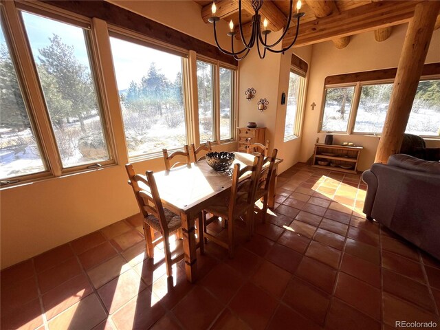 dining space featuring dark tile patterned floors, beam ceiling, and a notable chandelier