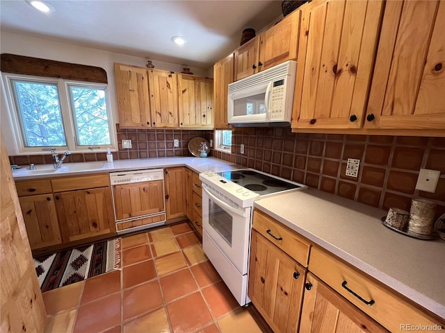 kitchen with light tile patterned floors, white appliances, a sink, light countertops, and backsplash