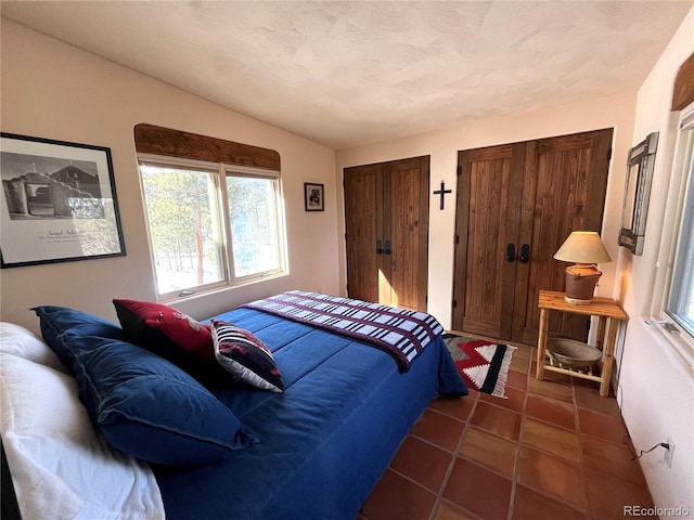 bedroom with two closets and dark tile patterned flooring