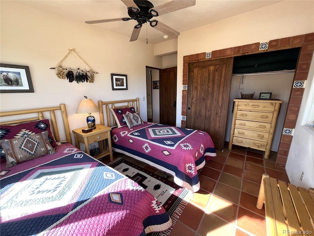 bedroom with dark tile patterned flooring, a closet, and a ceiling fan