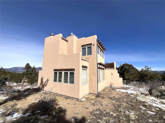 view of snow covered exterior with a chimney and stucco siding