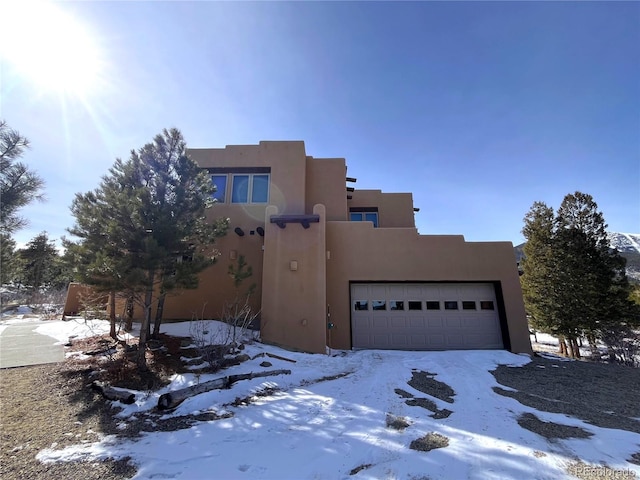 pueblo revival-style home featuring an attached garage and stucco siding