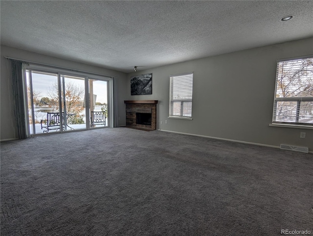 unfurnished living room with a fireplace, a textured ceiling, and dark carpet