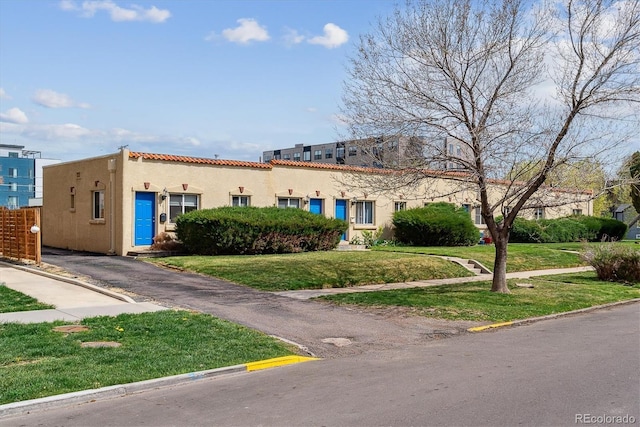 1804 Grove St, Denver, CO 80204 - mediterranean / spanish house featuring stucco siding, a front lawn, and a tile roof