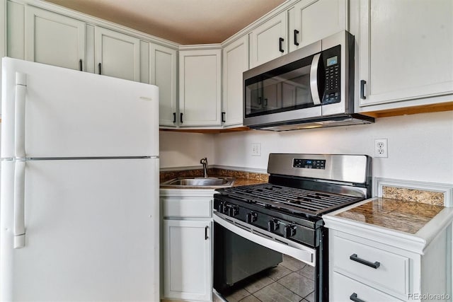 1804 Grove St, Denver, CO 80204 - kitchen featuring white cabinets, tile patterned floors, dark countertops, a sink, and appliances with stainless steel finishes