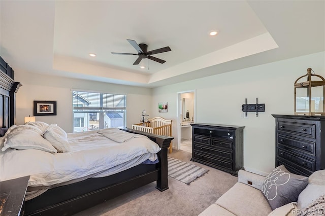 carpeted bedroom with a raised ceiling and ceiling fan