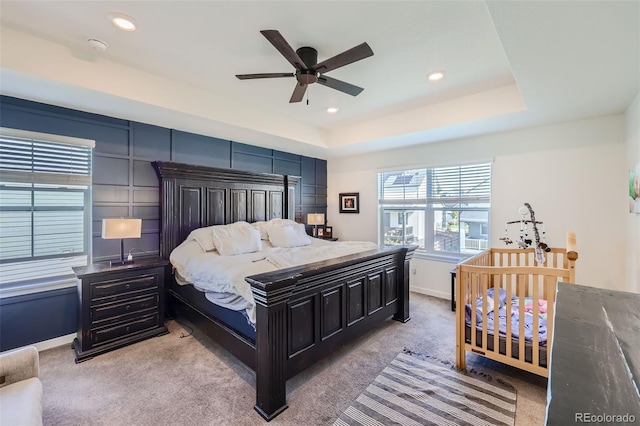 carpeted bedroom featuring a raised ceiling and ceiling fan