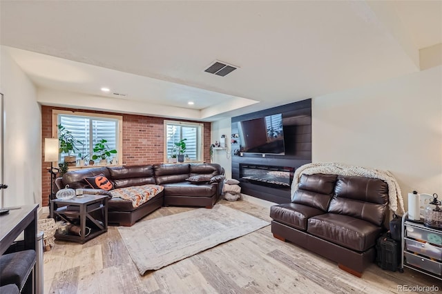 living room with a tray ceiling and light wood-type flooring