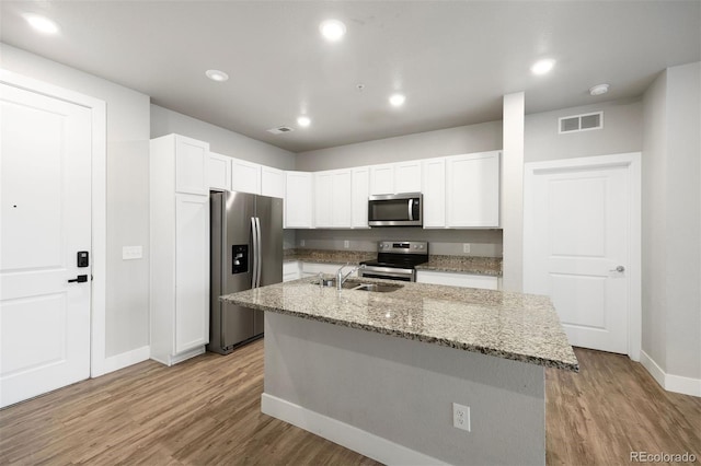 kitchen with appliances with stainless steel finishes, baseboards, a sink, light wood-style flooring, and recessed lighting