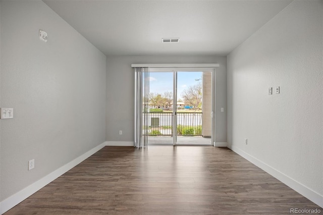 spare room featuring dark wood-style flooring and baseboards