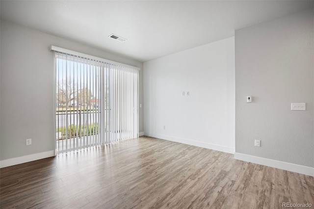 spare room featuring plenty of natural light, wood finished floors, and baseboards