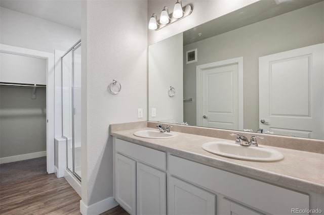 full bathroom featuring a stall shower, double vanity, wood finished floors, and baseboards