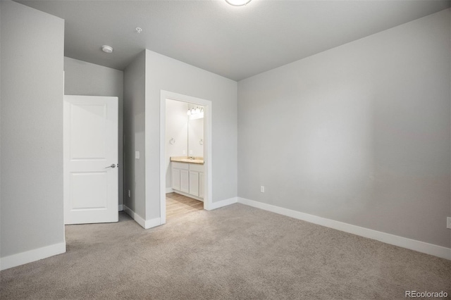 unfurnished bedroom with light carpet, baseboards, and ensuite bathroom