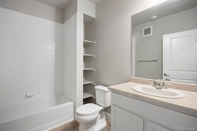 full bath with wood finished floors, toilet, vanity, a textured wall, and shower / tub combination