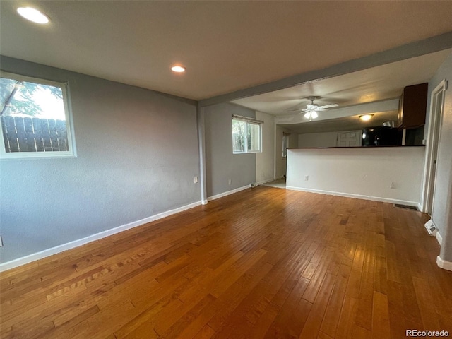 unfurnished living room with hardwood / wood-style floors, ceiling fan, and a healthy amount of sunlight