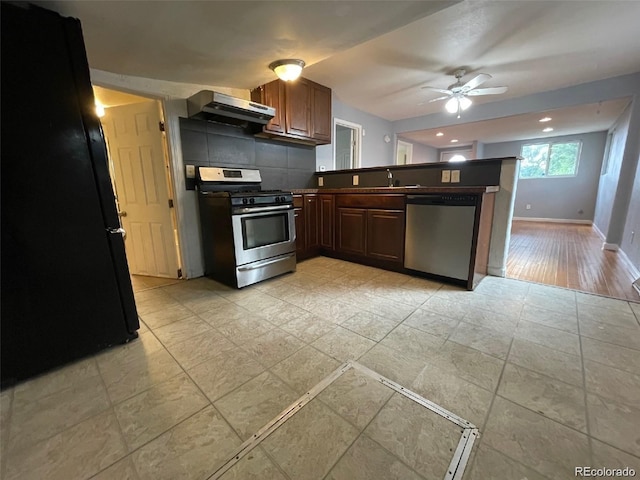 kitchen featuring exhaust hood, light hardwood / wood-style flooring, decorative backsplash, ceiling fan, and appliances with stainless steel finishes