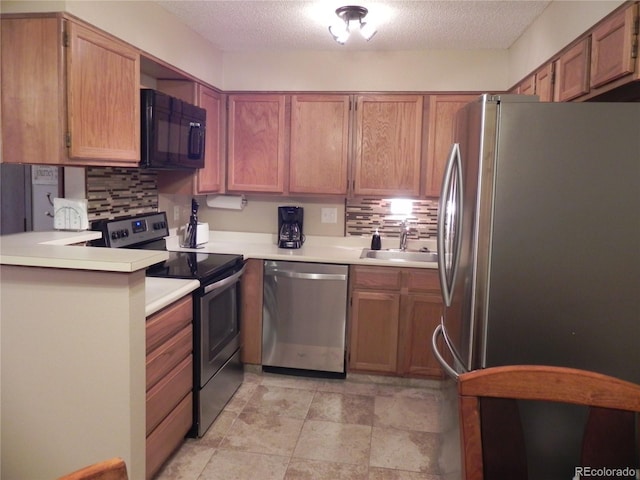 kitchen with sink, decorative backsplash, stainless steel appliances, and a textured ceiling