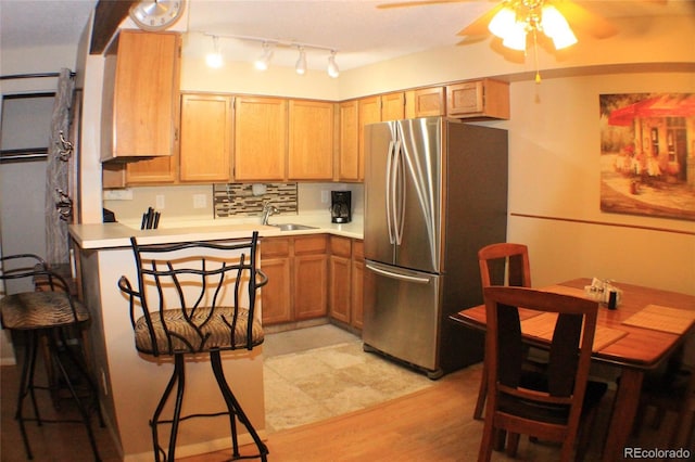 kitchen with stainless steel refrigerator, sink, backsplash, ceiling fan, and light hardwood / wood-style floors