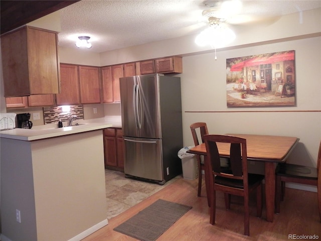 kitchen with backsplash, stainless steel fridge, a textured ceiling, and light wood-type flooring