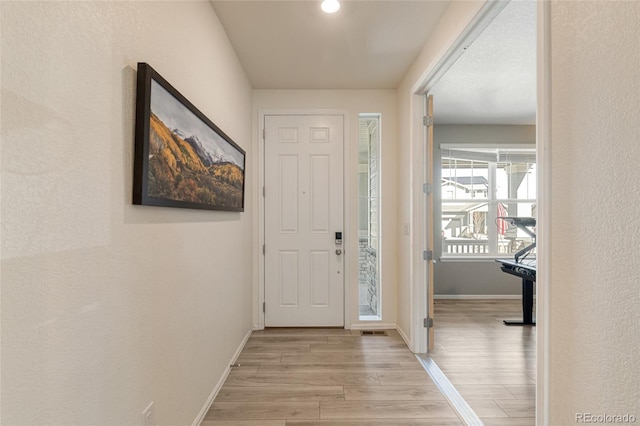 entryway with baseboards and light wood finished floors