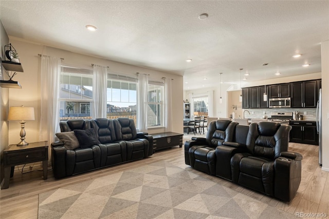 living room with recessed lighting, light wood-style floors, and a textured ceiling