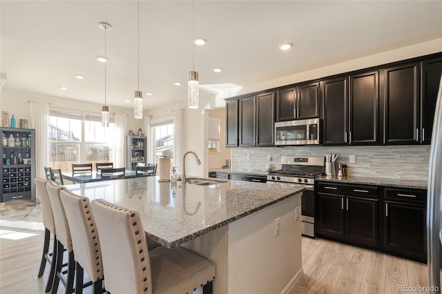 kitchen with a breakfast bar area, stone countertops, stainless steel appliances, and a sink