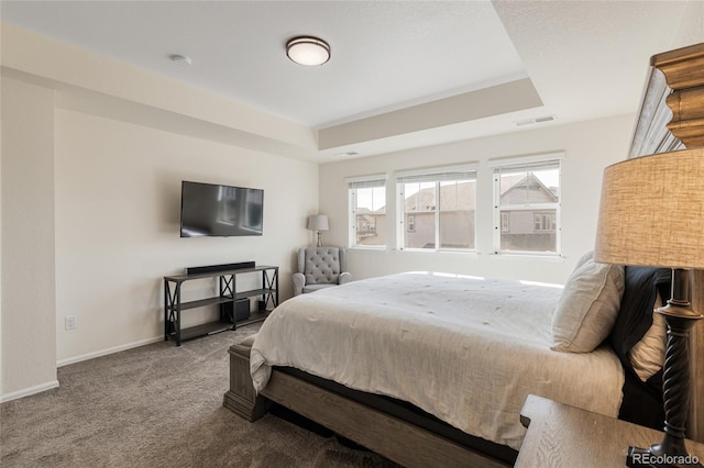 carpeted bedroom featuring a raised ceiling, baseboards, and visible vents