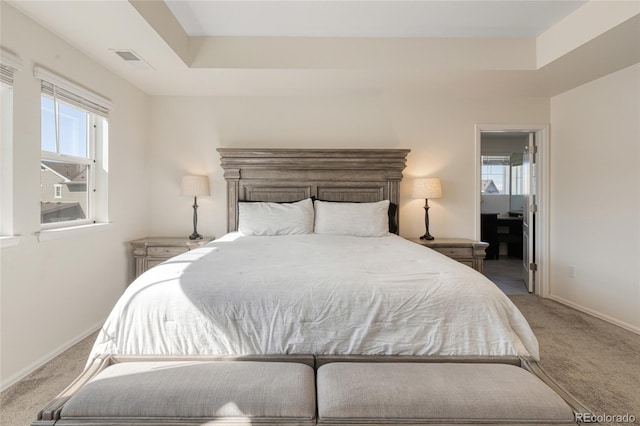 carpeted bedroom featuring visible vents, baseboards, and a tray ceiling