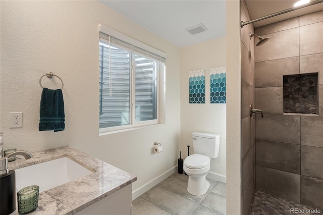 bathroom featuring vanity, toilet, visible vents, and a tile shower