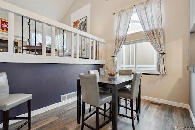 dining area with dark hardwood / wood-style floors and vaulted ceiling