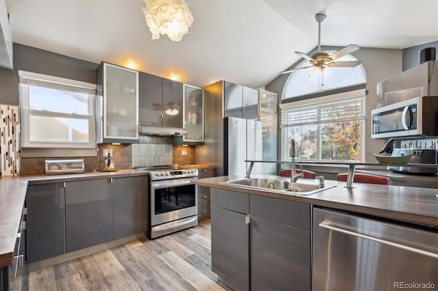 kitchen featuring appliances with stainless steel finishes, backsplash, gray cabinets, and lofted ceiling