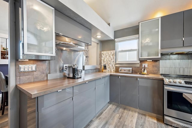 kitchen with wood counters, gray cabinets, exhaust hood, and stainless steel range