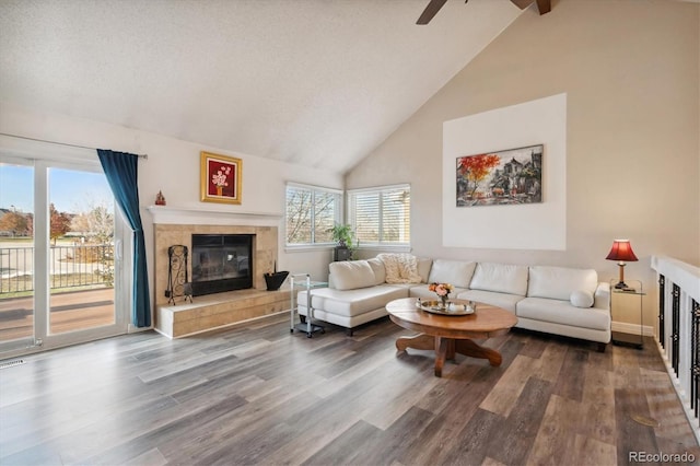 living room with lofted ceiling with beams, wood-type flooring, and a tiled fireplace