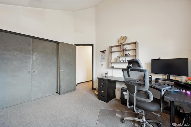 home office featuring a towering ceiling and light colored carpet