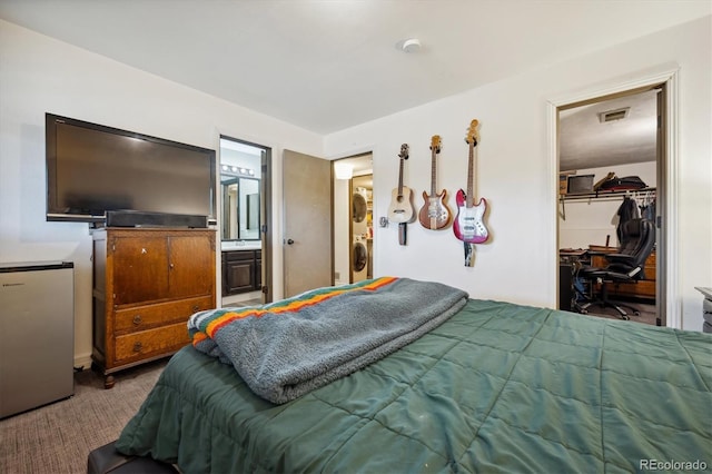 bedroom featuring carpet flooring, ensuite bath, stainless steel fridge, a walk in closet, and a closet