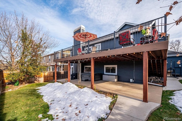 back of property with a lawn, a patio area, a deck, and a hot tub