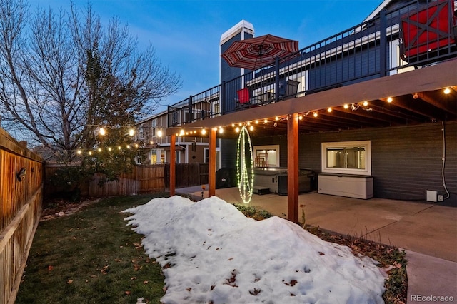 back house at dusk featuring a patio area, a balcony, and a hot tub