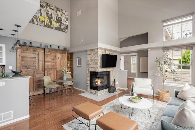 6858 Zenobia St Unit 9, Westminster, CO 80030 - living area with a high ceiling, wood finished floors, a barn door, baseboards, and a fireplace