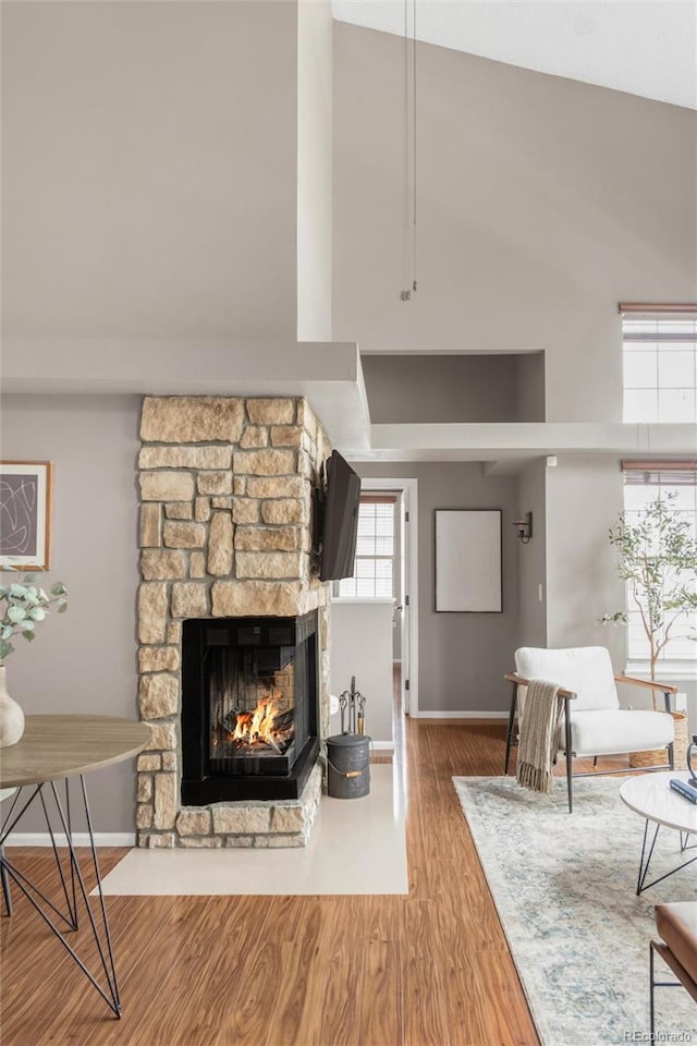 6858 Zenobia St Unit 9, Westminster, CO 80030 - living room featuring a towering ceiling, a stone fireplace, wood finished floors, and baseboards