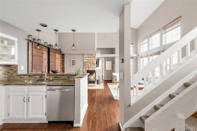 6858 Zenobia St Unit 9, Westminster, CO 80030 - kitchen with dishwasher, a sink, a peninsula, dark stone counters, and white cabinetry
