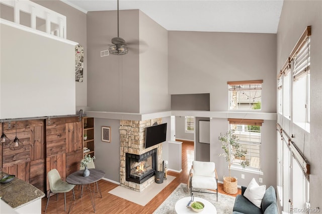 6858 Zenobia St Unit 9, Westminster, CO 80030 - living area with wood finished floors, a high ceiling, ceiling fan, a stone fireplace, and baseboards