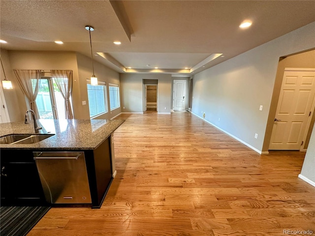 6765 Windbrook Ct, Colorado Springs, CO 80927 - kitchen with open floor plan, a tray ceiling, light wood-style floors, stone counters, and stainless steel dishwasher