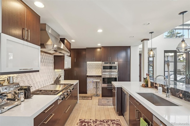 621 Kearney St, Denver, CO 80220 - kitchen with wall chimney range hood, a sink, light countertops, stainless steel gas stovetop, and pendant lighting