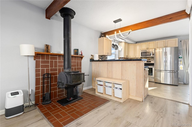 kitchen with pendant lighting, a wood stove, stainless steel appliances, light brown cabinets, and beam ceiling