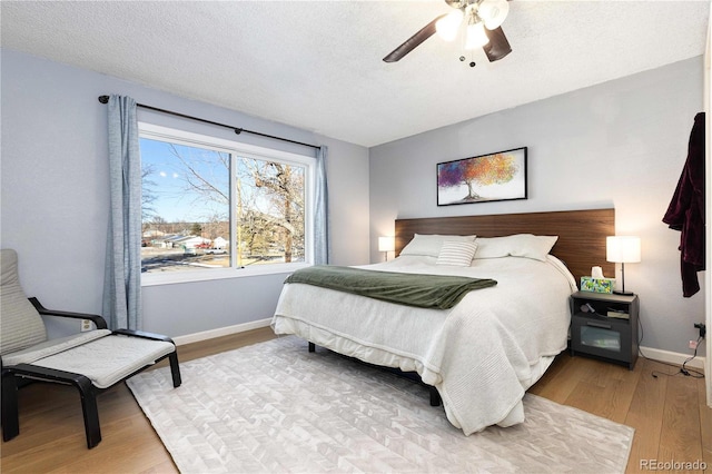 bedroom featuring ceiling fan, a textured ceiling, and light hardwood / wood-style flooring